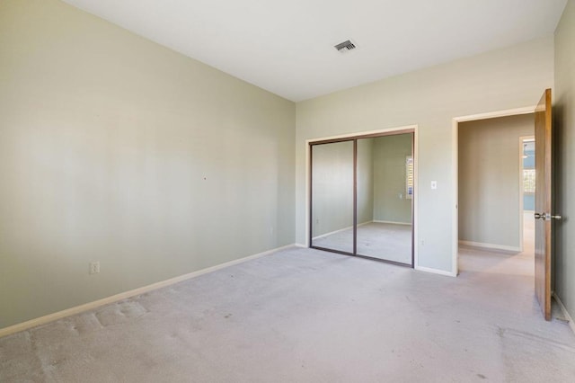 unfurnished bedroom featuring light carpet and a closet