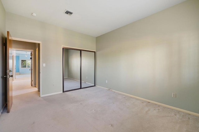 unfurnished bedroom featuring a closet and light colored carpet