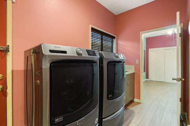 laundry room with washing machine and clothes dryer and cabinets