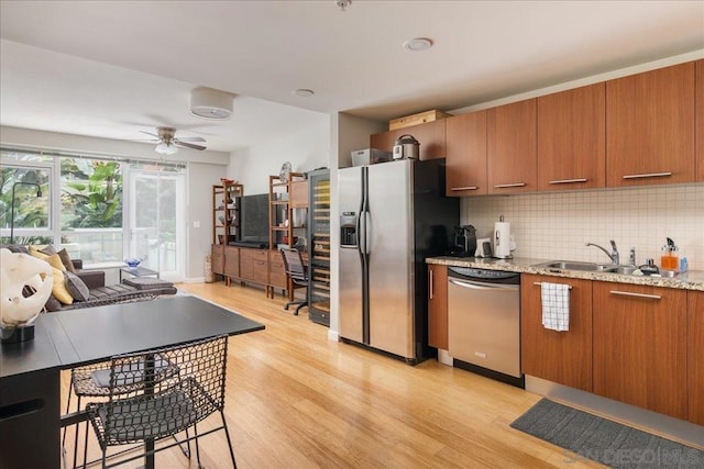 kitchen with tasteful backsplash, stainless steel appliances, ceiling fan, sink, and light hardwood / wood-style floors