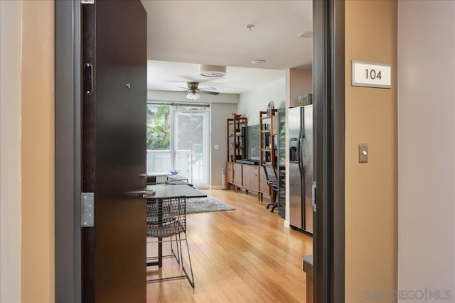 kitchen featuring ceiling fan, light hardwood / wood-style floors, stainless steel refrigerator with ice dispenser, and a breakfast bar