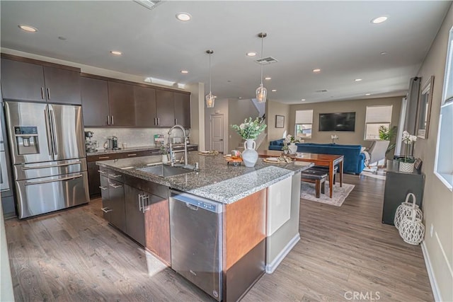 kitchen featuring appliances with stainless steel finishes, light hardwood / wood-style flooring, a kitchen island with sink, and sink