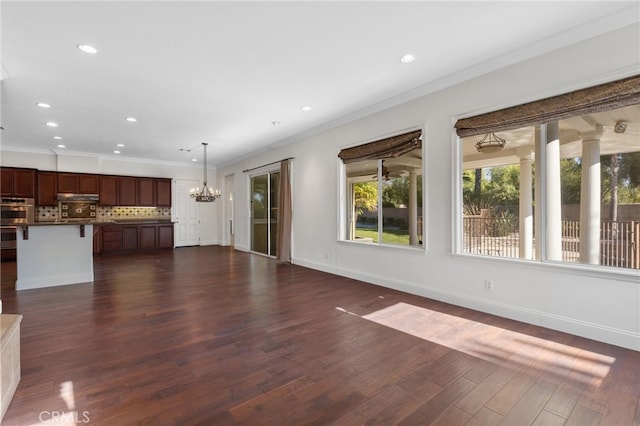 unfurnished living room featuring a notable chandelier, dark hardwood / wood-style flooring, and ornamental molding