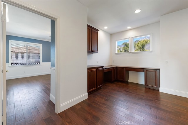 kitchen featuring ornamental molding, built in desk, and dark wood-type flooring