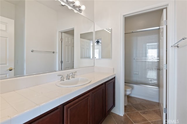 full bathroom featuring ceiling fan, vanity, bath / shower combo with glass door, and toilet