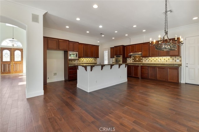 kitchen with dark hardwood / wood-style flooring, a breakfast bar area, appliances with stainless steel finishes, and an island with sink