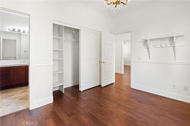 unfurnished bedroom with dark wood-type flooring, sink, crown molding, ensuite bath, and a notable chandelier