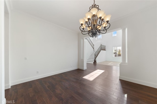 unfurnished living room featuring dark hardwood / wood-style floors, ornate columns, ornamental molding, and a notable chandelier