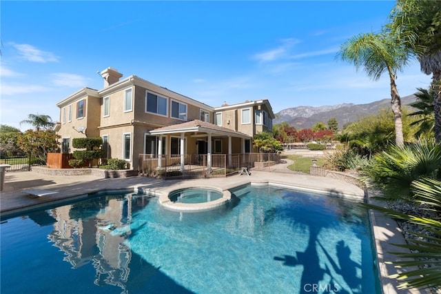 view of swimming pool with a mountain view, a patio area, and an in ground hot tub