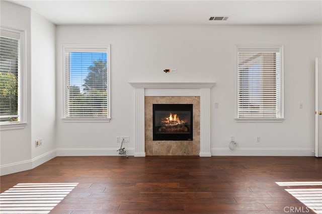 unfurnished living room featuring a tile fireplace and dark hardwood / wood-style flooring