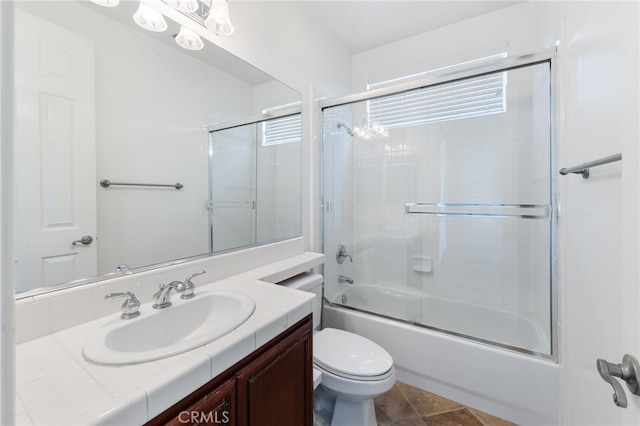 full bathroom with combined bath / shower with glass door, toilet, and vanity