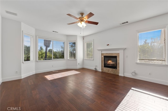 unfurnished living room with a tile fireplace, dark wood-type flooring, and a healthy amount of sunlight