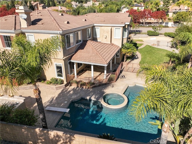 rear view of house featuring a pool with hot tub and a patio