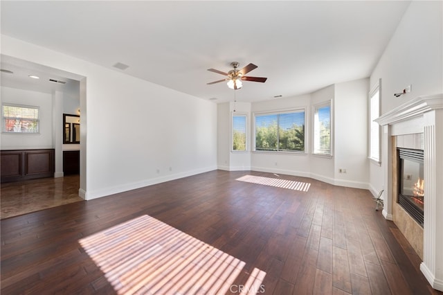 unfurnished living room with a tile fireplace, dark hardwood / wood-style floors, and ceiling fan