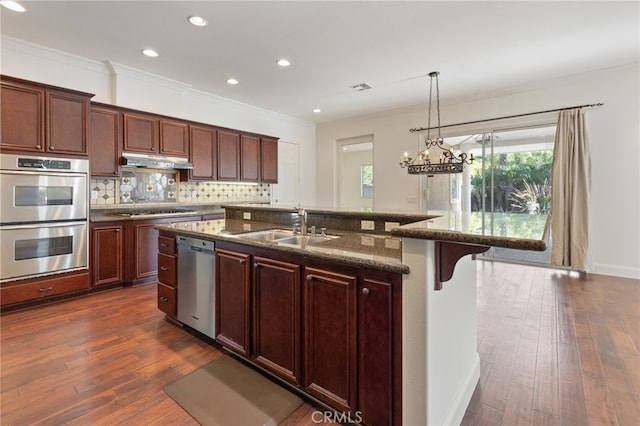 kitchen with dark hardwood / wood-style flooring, sink, an island with sink, and stainless steel appliances