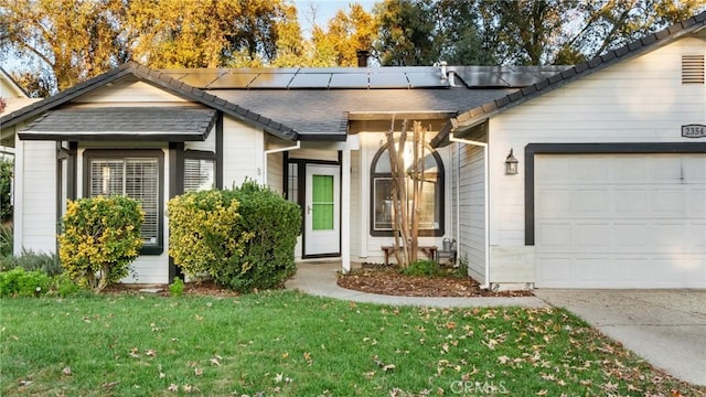 single story home with a garage, a front yard, and solar panels