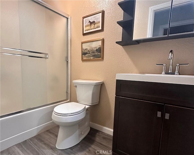 full bathroom featuring combined bath / shower with glass door, vanity, wood-type flooring, and toilet