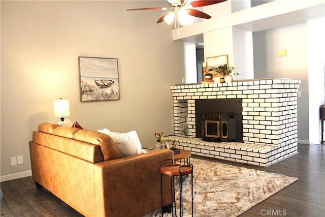 living room featuring ceiling fan, dark hardwood / wood-style flooring, and a wood stove