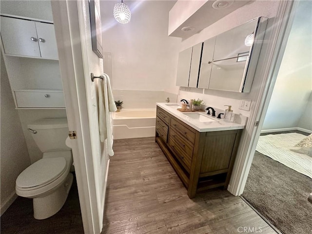 bathroom featuring toilet, vanity, a bathtub, and hardwood / wood-style flooring