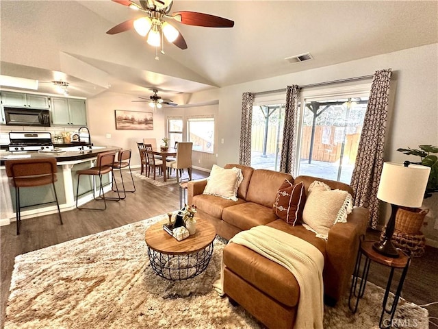 living room featuring vaulted ceiling, ceiling fan, and dark hardwood / wood-style floors