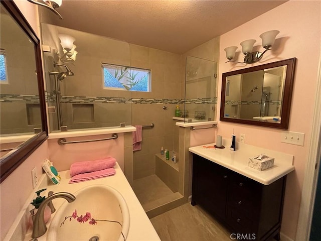 bathroom with tiled shower, a textured ceiling, and vanity