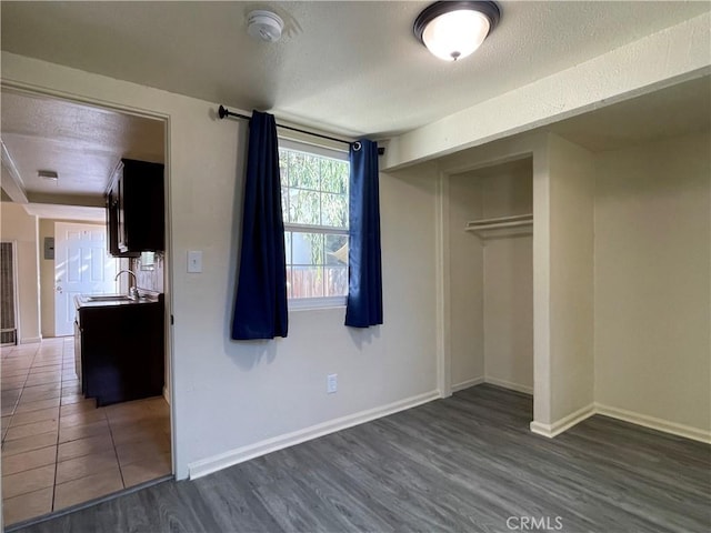 unfurnished bedroom with a textured ceiling, a closet, dark hardwood / wood-style floors, and sink