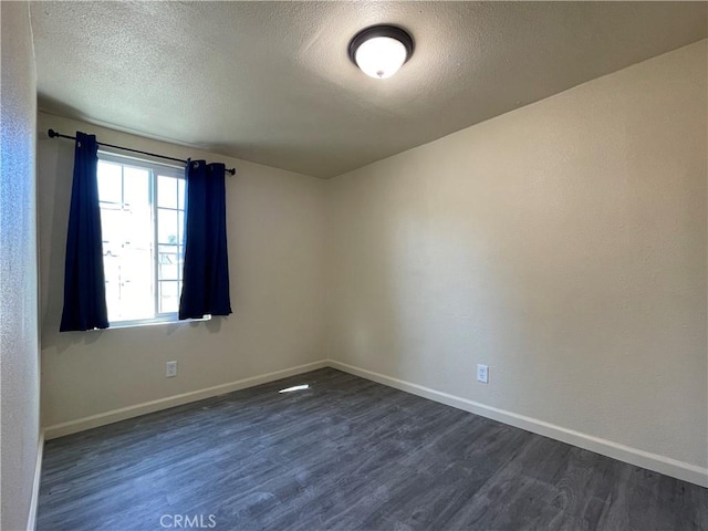 unfurnished room with dark hardwood / wood-style floors and a textured ceiling