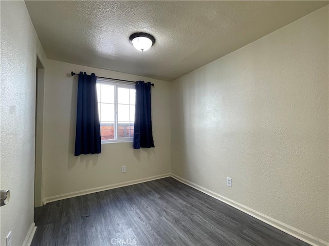 spare room with dark wood-type flooring and a textured ceiling