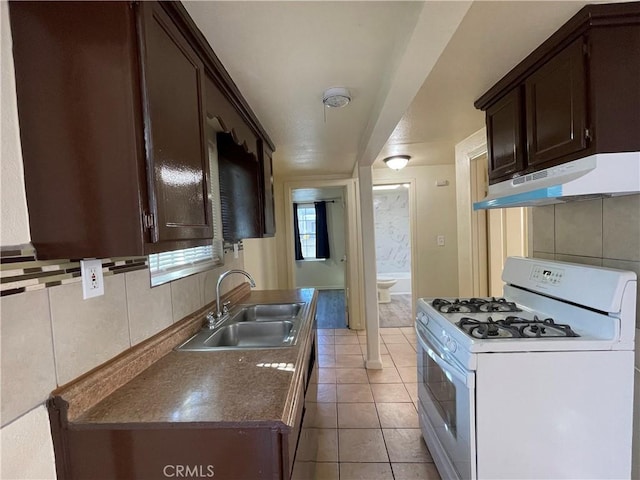 kitchen featuring sink, light tile patterned floors, tasteful backsplash, dark brown cabinetry, and gas range gas stove