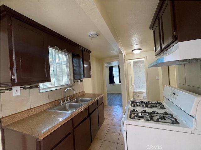 kitchen featuring sink, tasteful backsplash, white range with gas stovetop, extractor fan, and dark brown cabinets