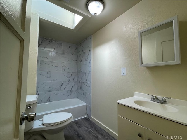 full bathroom featuring a skylight, vanity, hardwood / wood-style flooring, toilet, and tiled shower / bath