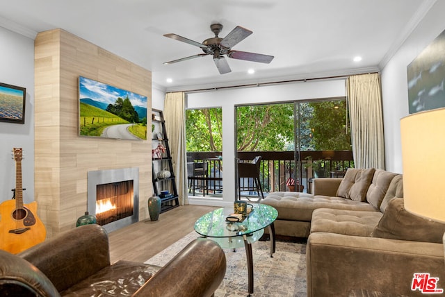 living room featuring ceiling fan, a fireplace, light hardwood / wood-style floors, and ornamental molding