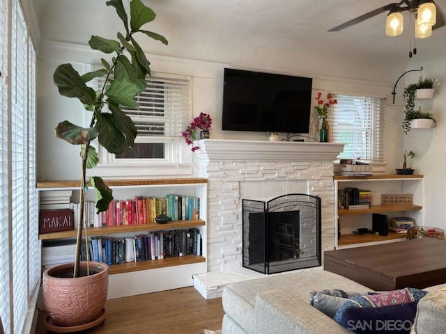 living room featuring ceiling fan, a fireplace, crown molding, and hardwood / wood-style flooring