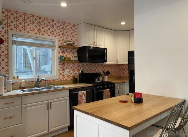 kitchen with black appliances, white cabinetry, sink, and wooden counters