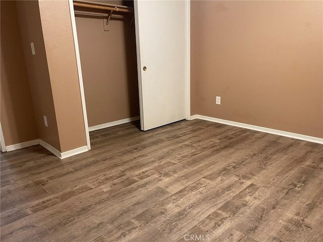 unfurnished bedroom with dark hardwood / wood-style flooring and a closet