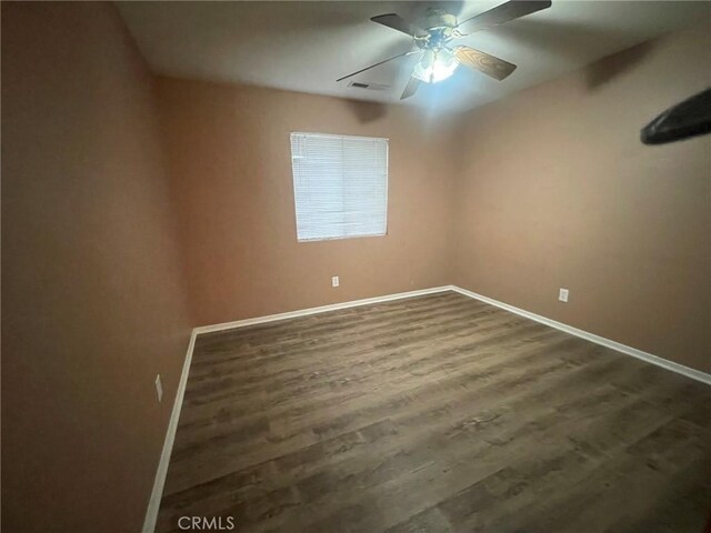 unfurnished room with ceiling fan and dark wood-type flooring