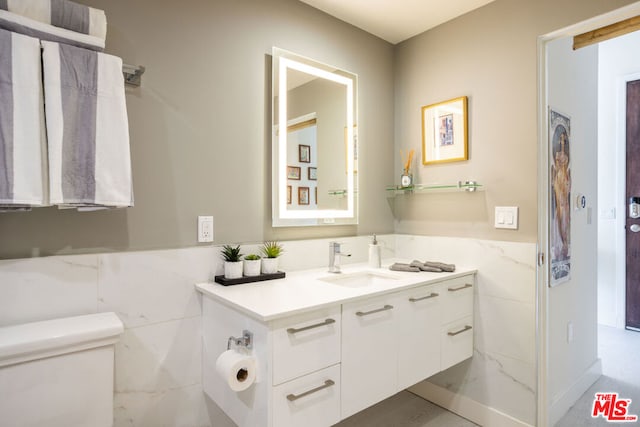 bathroom with vanity, toilet, and tile walls