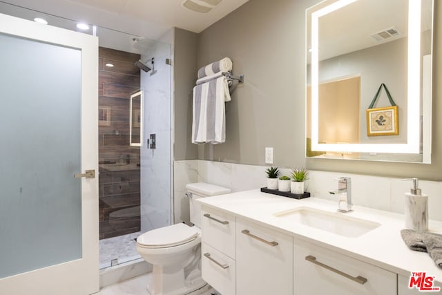 bathroom featuring vanity, a shower with shower door, and toilet