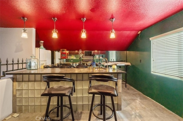 bar featuring pendant lighting, a textured ceiling, and vaulted ceiling