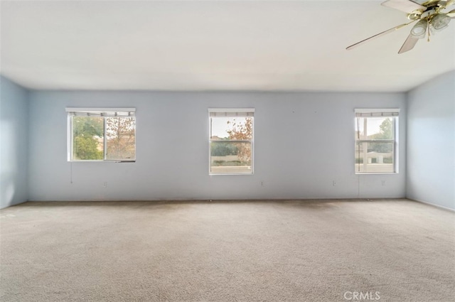 carpeted spare room with ceiling fan and plenty of natural light