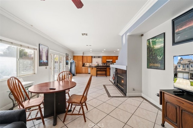 tiled dining area with ceiling fan and crown molding