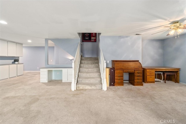 interior space with ceiling fan and light colored carpet