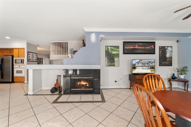 interior space with ceiling fan, light tile patterned floors, a tile fireplace, and ornamental molding