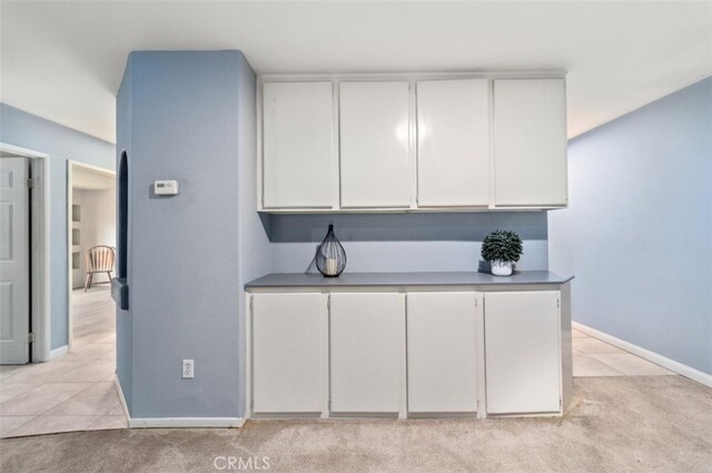 kitchen featuring light colored carpet and white cabinetry