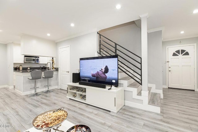 living room with light wood-type flooring and crown molding