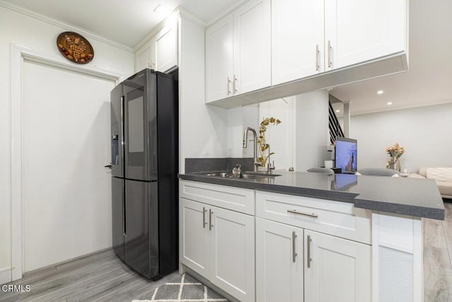 kitchen featuring stainless steel fridge, light wood-type flooring, and white cabinetry