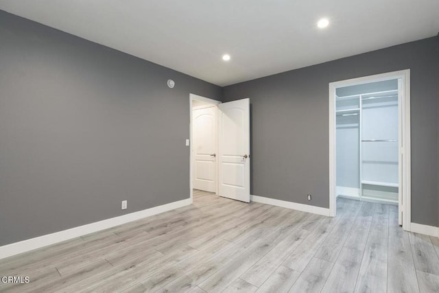 unfurnished bedroom featuring light hardwood / wood-style floors, a spacious closet, and a closet