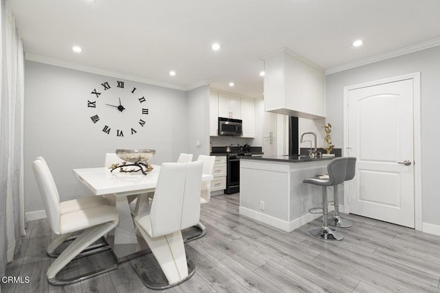 kitchen featuring light hardwood / wood-style flooring, kitchen peninsula, black range with gas cooktop, a breakfast bar, and white cabinets