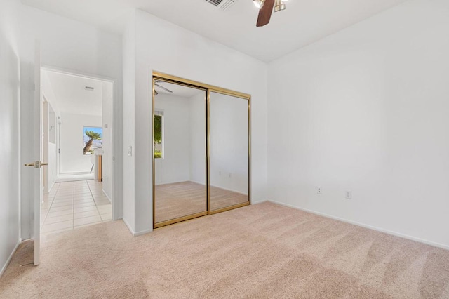 unfurnished bedroom featuring light carpet, a closet, and ceiling fan