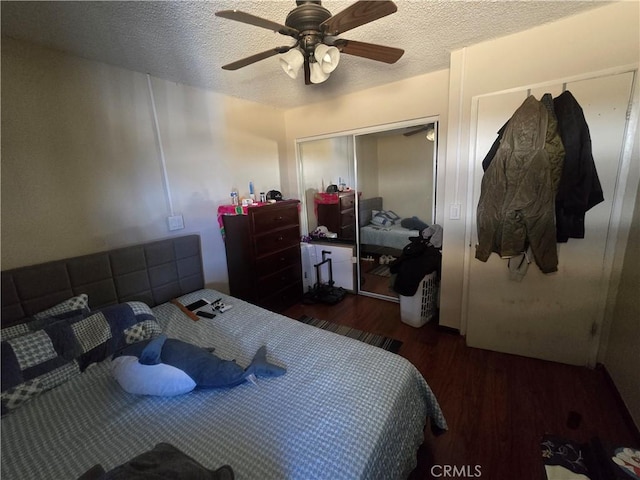 bedroom with a textured ceiling, dark wood-type flooring, a closet, and ceiling fan